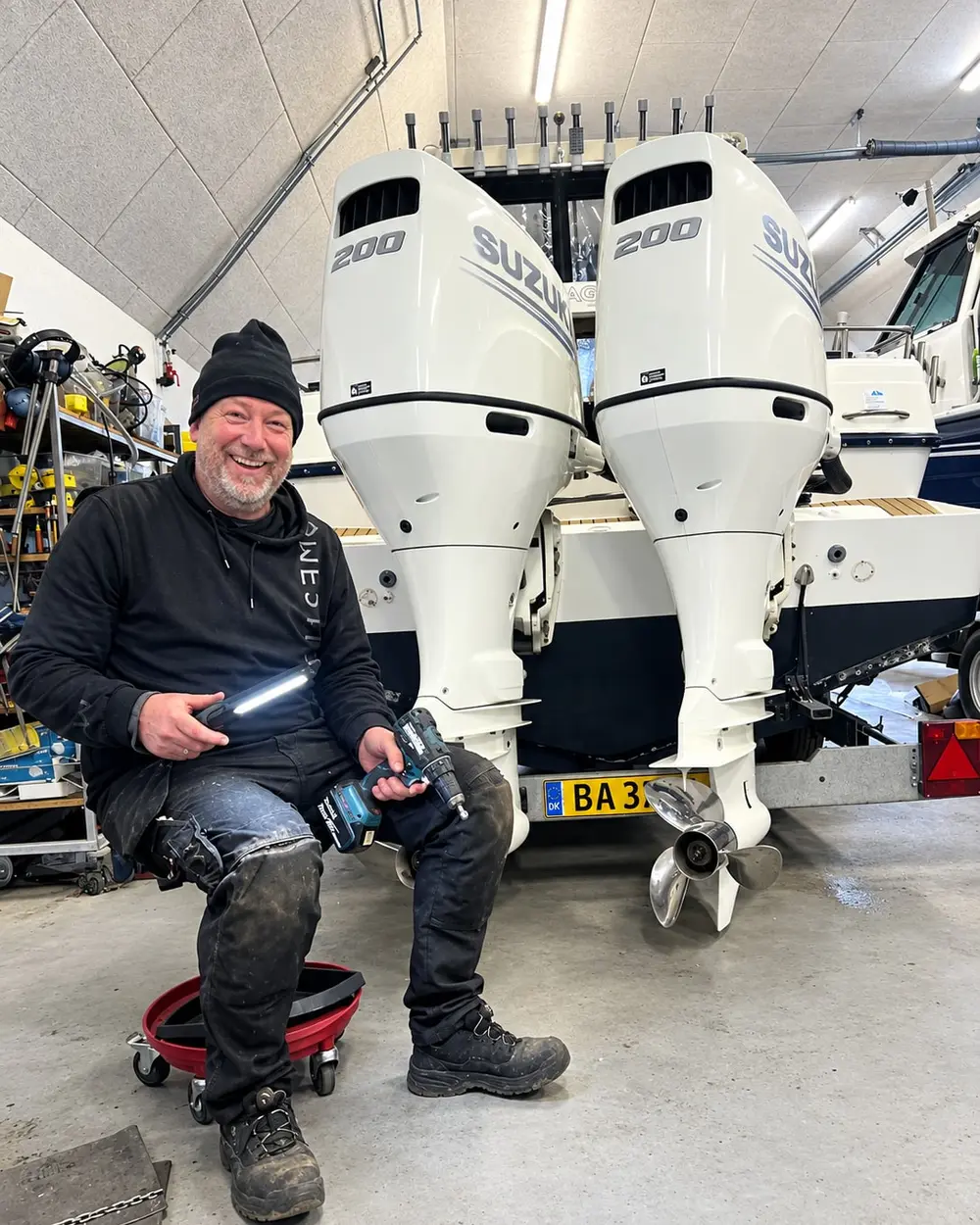 Rasmus Almbjørn med arbejdslampe og skruemaskine foran to nye Suzuki-motorer